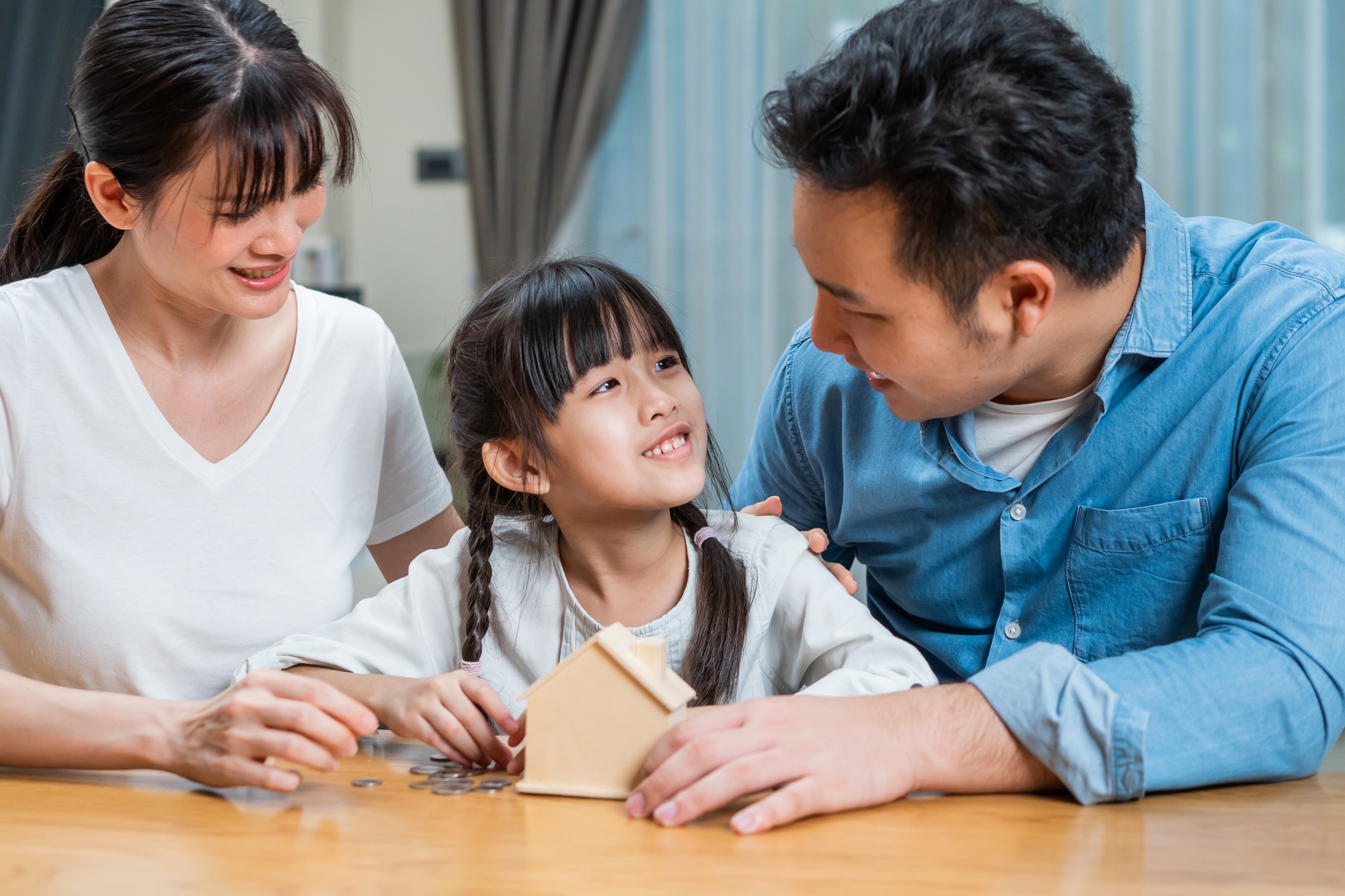 Asian kid enjoy put coins in piggy bank with parents and learn to manage financial plan